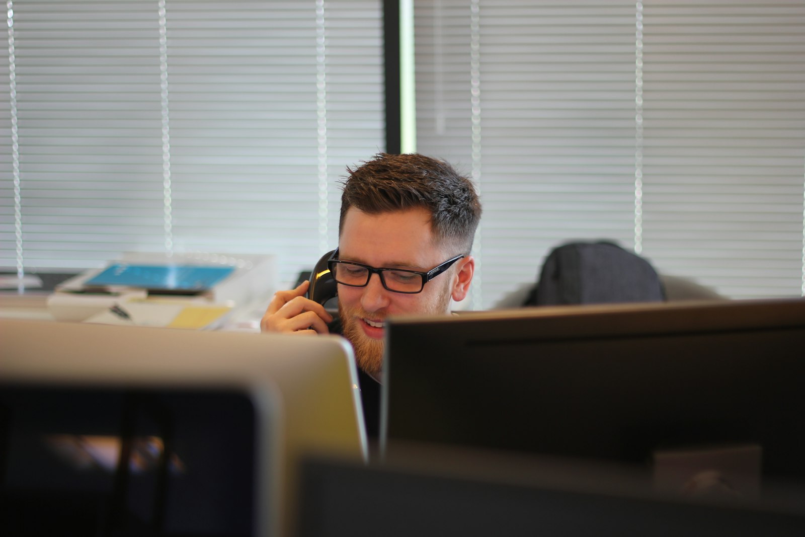 Professional answering an inbound business call at a multi-monitor desk